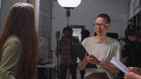 Director-De-Cine-Hablando-Con-Actores-Masculinos-Y-Femeninos-Sosteniendo-Guiones-Ensayando-Para-Filmar-Una-Película-O-Un-Video-En-El-Estudio-6